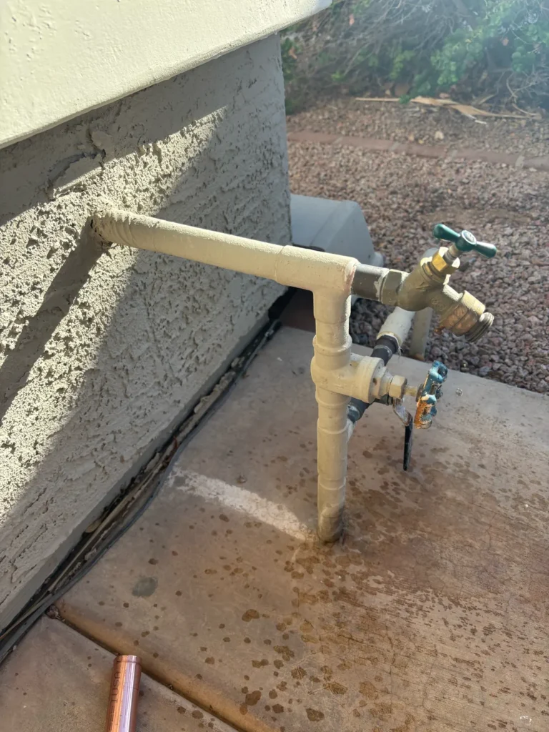 Leaking outdoor hose bib and shut-off valve on painted pipe before repair
